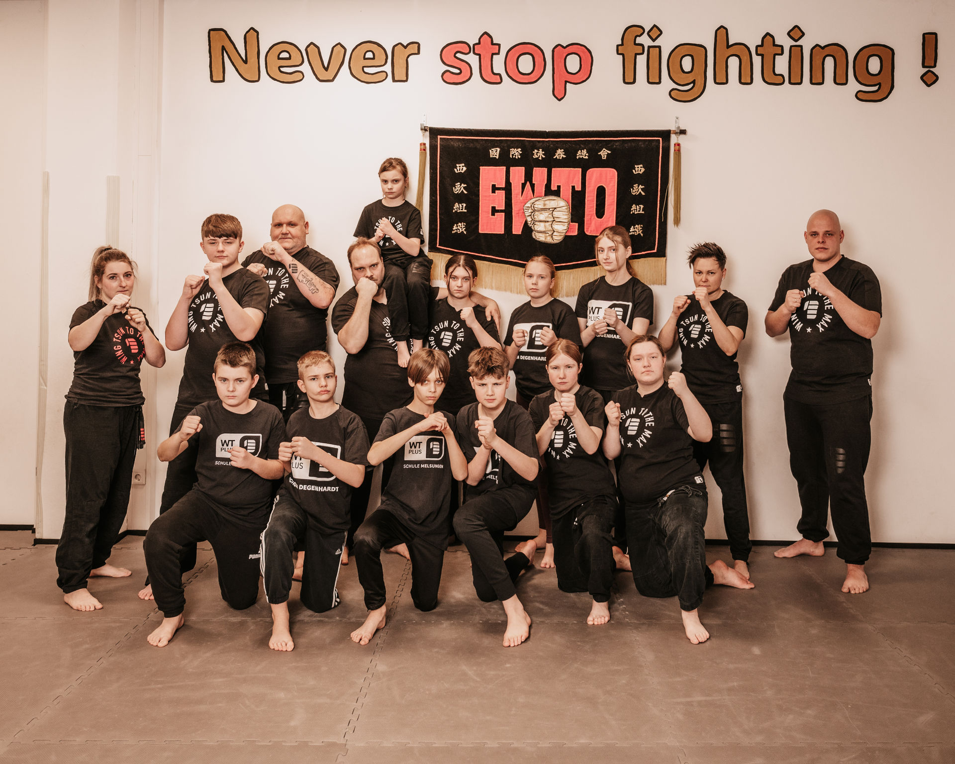 WTplus Gruppe beim Training vor dem EWTO-Banner – Never stop fighting