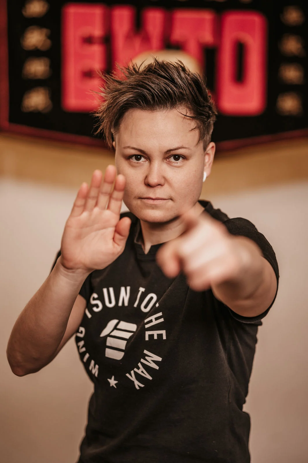 Entschlossene WingTsun-Uebende vor dem EWTO-Zeichen